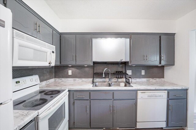 6900 Unity Ave N, Brooklyn Center, MN 55429 - kitchen featuring white appliances, a sink, gray cabinetry, tasteful backsplash, and light countertops