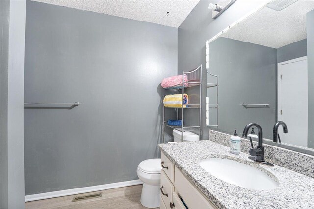 6900 Unity Ave N, Brooklyn Center, MN 55429 - half bathroom featuring wood finished floors, toilet, a textured ceiling, baseboards, and vanity