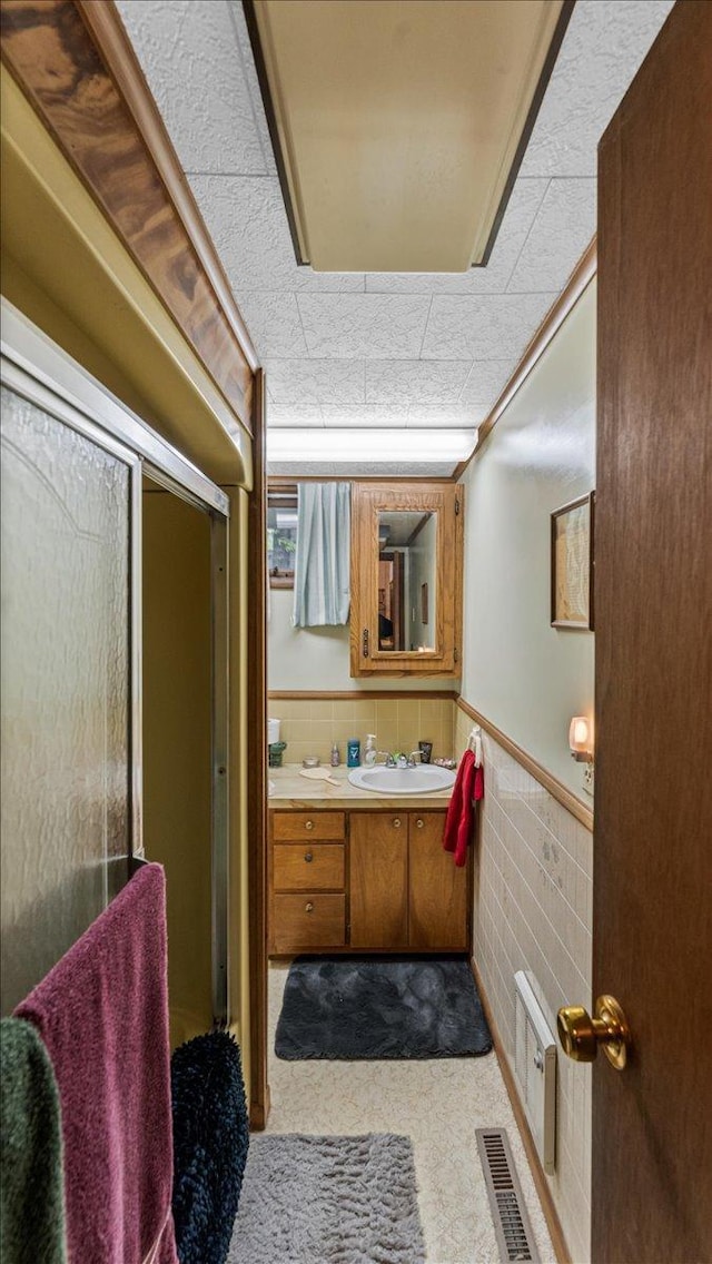 19157 181st Ave, Long Prairie, MN 56347 - bathroom featuring vanity, a wainscoted wall, tile walls, and an enclosed shower
