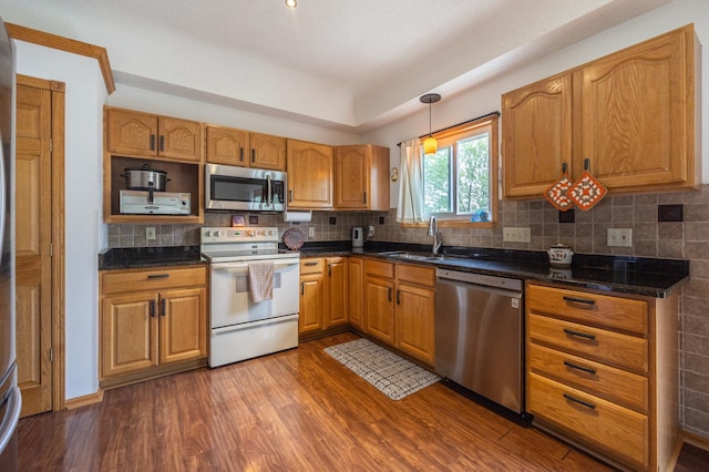 kitchen featuring stainless steel appliances, a sink, dark wood-type flooring, tasteful backsplash, and brown cabinetry