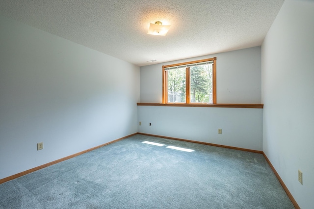 carpeted spare room with a textured ceiling and baseboards