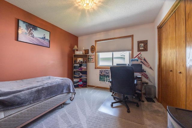 bedroom with light colored carpet, a desk, a textured ceiling, baseboards, and a closet
