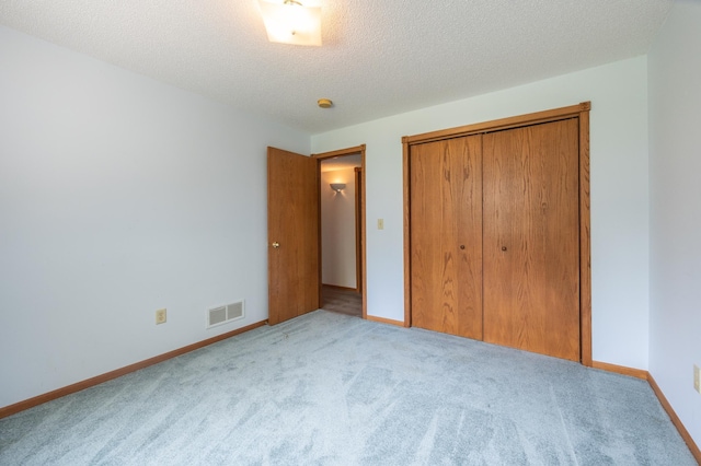 unfurnished bedroom featuring carpet floors, a closet, baseboards, and a textured ceiling