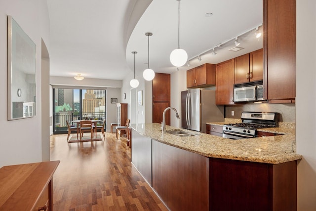 100 3rd Ave S Unit 1107, Minneapolis, MN 55401 - kitchen with appliances with stainless steel finishes, a sink, wood finished floors, light stone counters, and brown cabinets