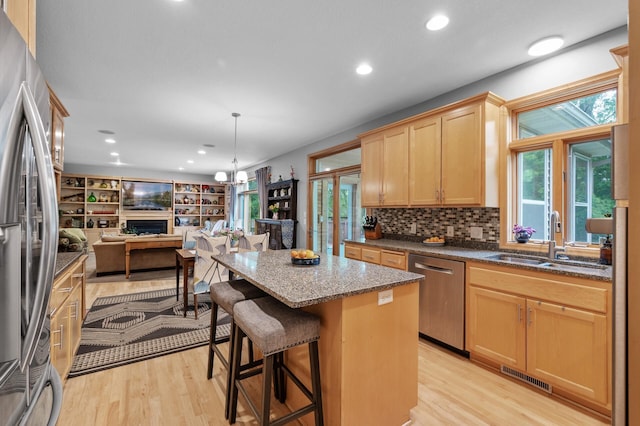 1665 3rd St SW, New Brighton, MN 55112 - kitchen with appliances with stainless steel finishes, a sink, open floor plan, dark stone countertops, and light wood finished floors