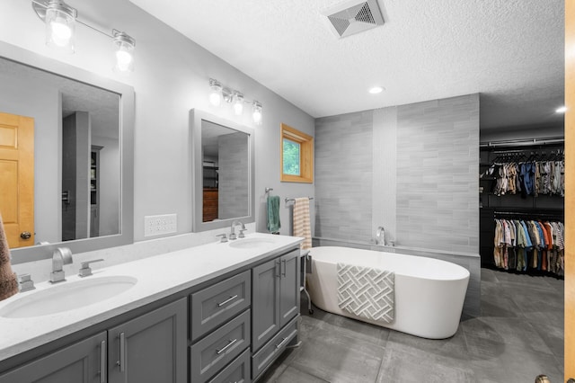 1665 3rd St SW, New Brighton, MN 55112 - full bathroom with double vanity, a textured ceiling, a freestanding tub, a walk in closet, and tile walls