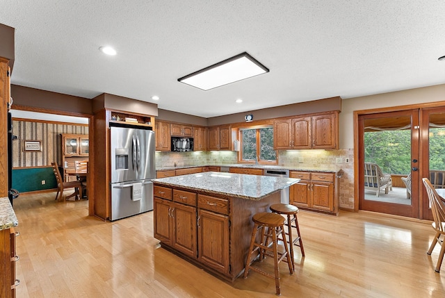2501 112th St, Bloomington, MN 55431 - kitchen featuring stainless steel fridge, black microwave, light wood finished floors, a sink, and a textured ceiling