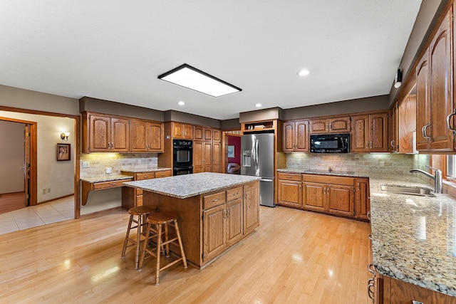 2501 112th St, Bloomington, MN 55431 - kitchen with black appliances, a sink, a center island, decorative backsplash, and a breakfast bar