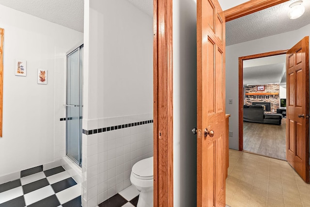 2501 112th St, Bloomington, MN 55431 - ensuite bathroom featuring a shower stall, a textured ceiling, a brick fireplace, tile patterned floors, and tile walls