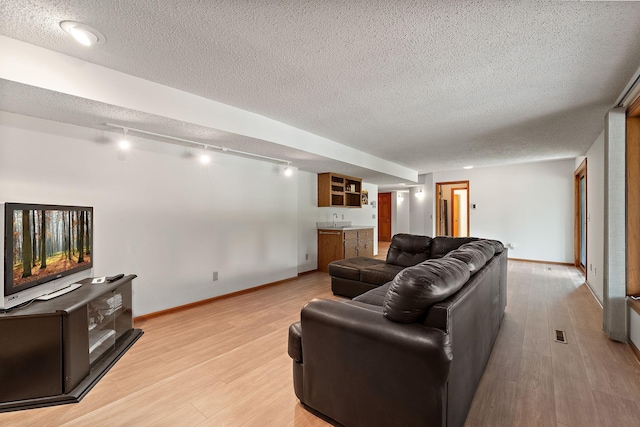 2501 112th St, Bloomington, MN 55431 - living room featuring wet bar, light wood-style flooring, baseboards, and a textured ceiling