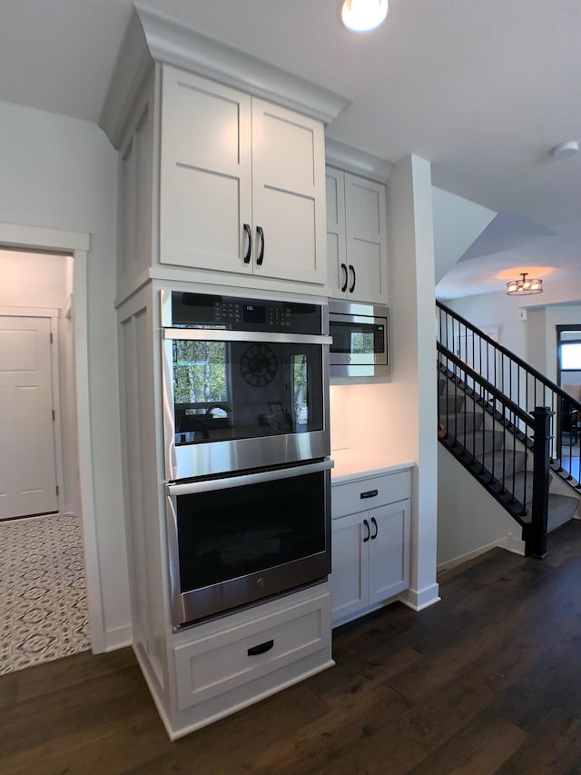 4605 130th Ln NE, Blaine, MN 55449 - kitchen with stainless steel appliances, light countertops, dark wood-style floors, baseboards, and white cabinetry