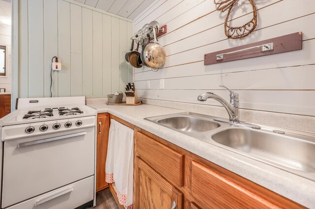 23873 Arcade Loop, Crow Wing Lake Twp, MN 56464 - kitchen with white gas range oven, wood walls, a sink, light countertops, and brown cabinets