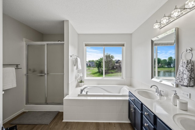 2940 Tiflawn Ct, Shakopee, MN 55379 - bathroom with wood finished floors, a bath, a stall shower, a textured ceiling, and double vanity