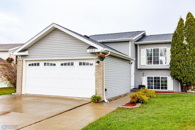 view of front of property featuring concrete driveway, an attached garage, a front yard, and a shingled roof