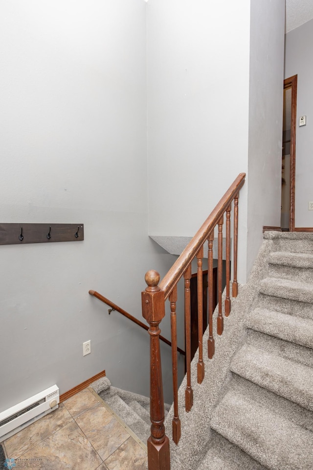 stairway featuring a baseboard radiator and stone finish floors