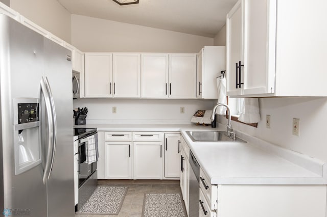 kitchen featuring stainless steel appliances, a sink, vaulted ceiling, white cabinets, and light countertops