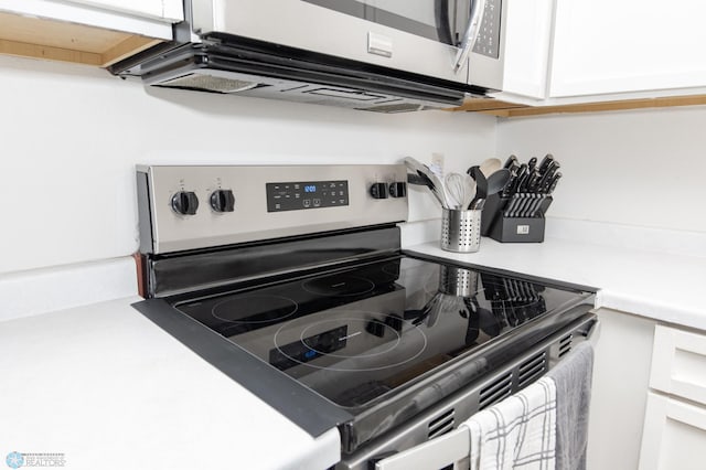 kitchen view of appliances with stainless steel finishes, light countertops, and white cabinets