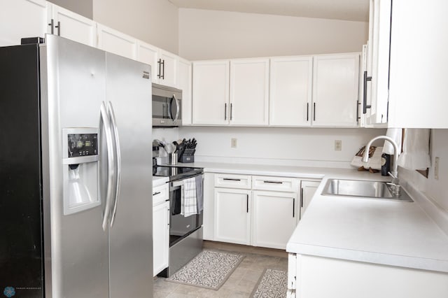 kitchen with stainless steel appliances, a sink, lofted ceiling, white cabinetry, and light countertops