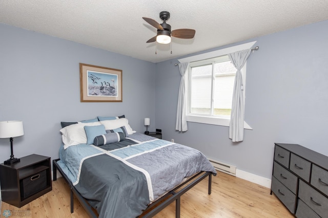 bedroom featuring a baseboard radiator, light wood finished floors, a textured ceiling, a ceiling fan, and baseboards