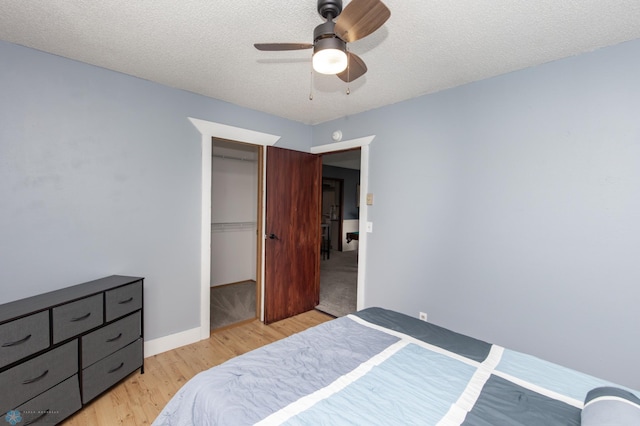 bedroom with light wood-style flooring, a textured ceiling, a ceiling fan, and a closet