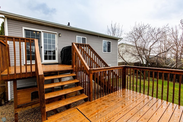 wooden deck featuring stairs and a lawn