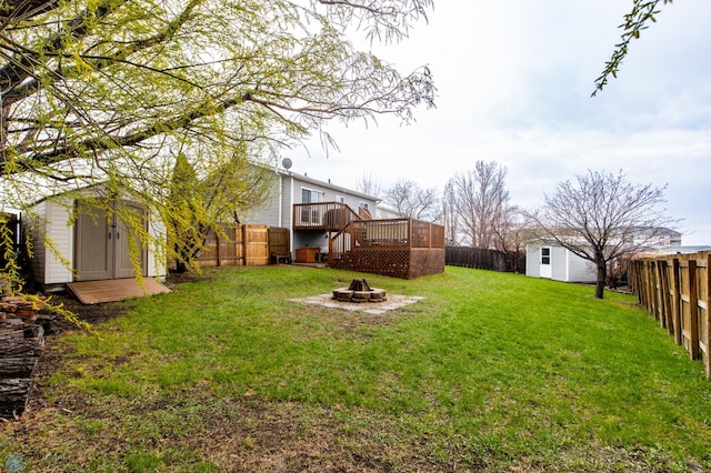 view of yard with a fire pit, a storage shed, a wooden deck, and an outbuilding