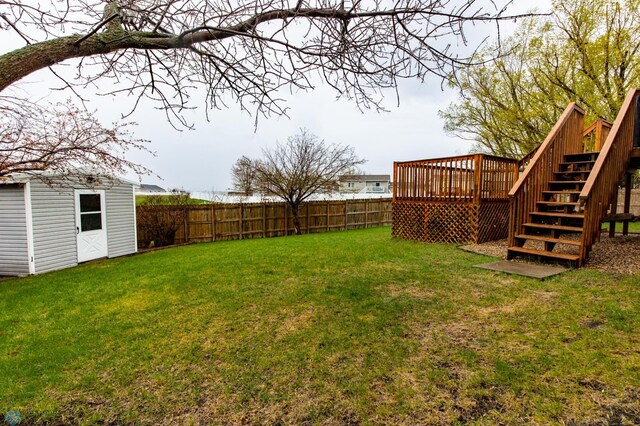 view of yard featuring stairs, a deck, an outdoor structure, and a storage shed