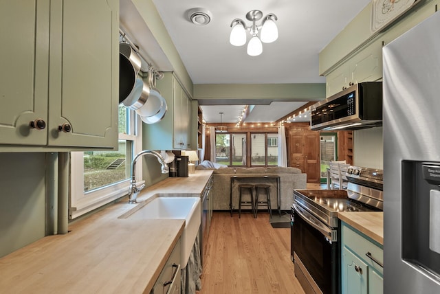 4236 Salem Ave, Saint Louis Park, MN 55416 - kitchen with green cabinets, stainless steel appliances, wooden counters, a chandelier, and light wood-type flooring