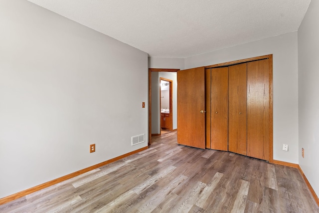 9013 91st St S, Cottage Grove, MN 55016 - unfurnished bedroom with light wood-type flooring, a closet, and a textured ceiling