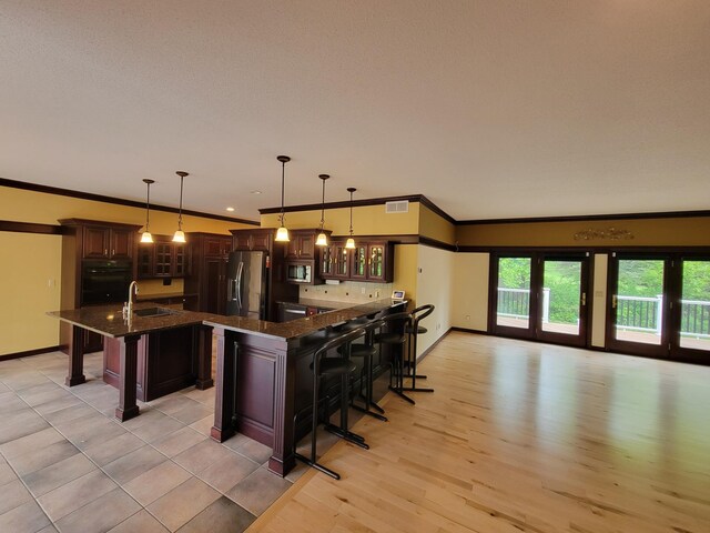 1605 26th St SE, Saint Cloud, MN 56304 - kitchen featuring stainless steel appliances, a breakfast bar, ornamental molding, glass insert cabinets, and dark brown cabinets