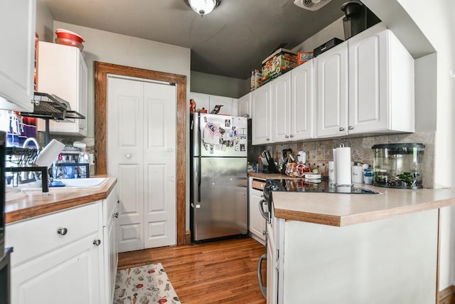 kitchen with freestanding refrigerator, white cabinetry, backsplash, light wood-style flooring, and light countertops