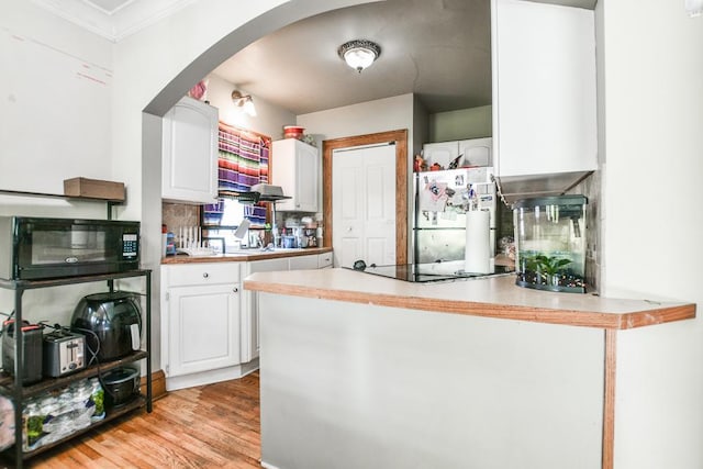 kitchen with black appliances, white cabinetry, a peninsula, arched walkways, and crown molding