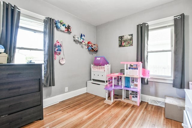 bedroom with light wood-style floors, baseboards, and multiple windows