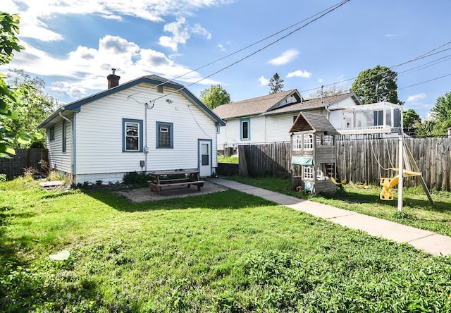rear view of house featuring a playground and a chimney