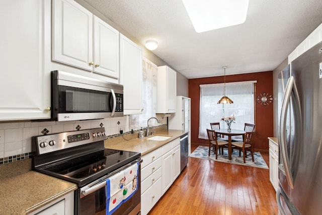 14650 Bloomfield Path, Rosemount, MN 55068 - kitchen with stainless steel appliances, a sink, white cabinetry, backsplash, and light wood-style flooring