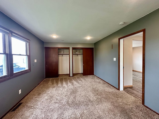 210 160th Ave, Osborne Twp, MN 56128 - unfurnished bedroom with multiple closets, light carpet, and baseboards
