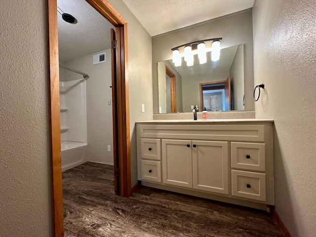 210 160th Ave, Osborne Twp, MN 56128 - bathroom featuring a textured wall, wood finished floors, vanity, shower / bath combination, and a textured ceiling