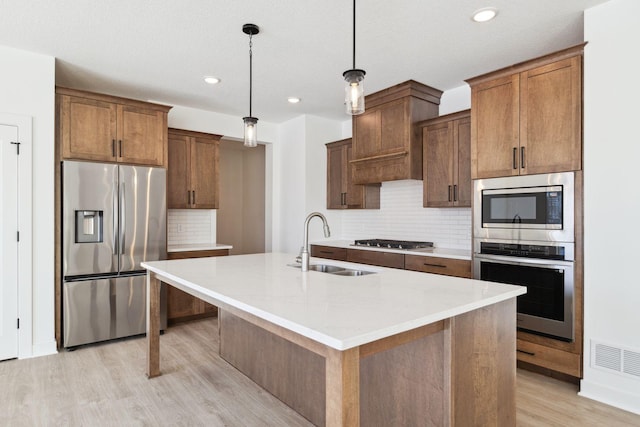 11781 34th St N, Lake Elmo, MN 55042 - kitchen with appliances with stainless steel finishes, a sink, light wood-type flooring, decorative backsplash, and a center island with sink