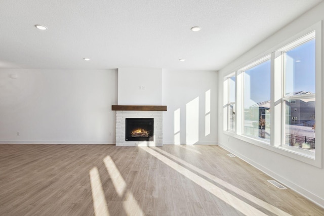 11781 34th St N, Lake Elmo, MN 55042 - unfurnished living room with a stone fireplace, light wood finished floors, baseboards, and recessed lighting