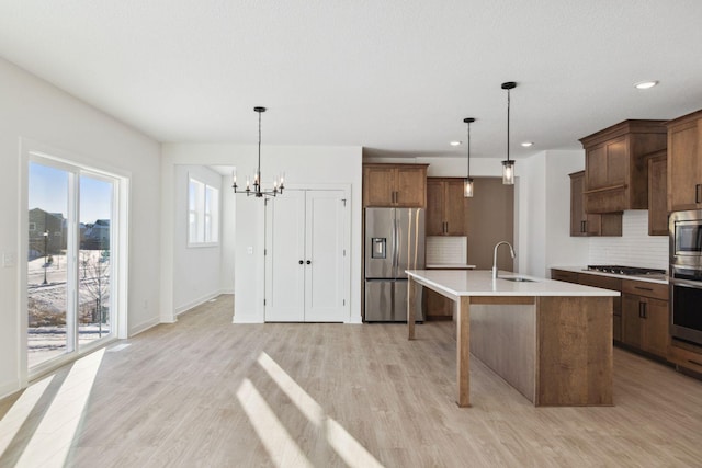 11781 34th St N, Lake Elmo, MN 55042 - kitchen with appliances with stainless steel finishes, a sink, decorative backsplash, a chandelier, and light countertops