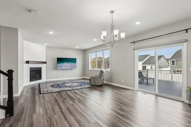18378 Grasshopper Dr, Lakeville, MN 55044 - unfurnished living room featuring wood finished floors, a chandelier, baseboards, recessed lighting, and a large fireplace