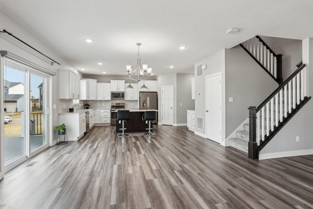 18378 Grasshopper Dr, Lakeville, MN 55044 - kitchen with appliances with stainless steel finishes, wood finished floors, a breakfast bar area, baseboards, and light countertops