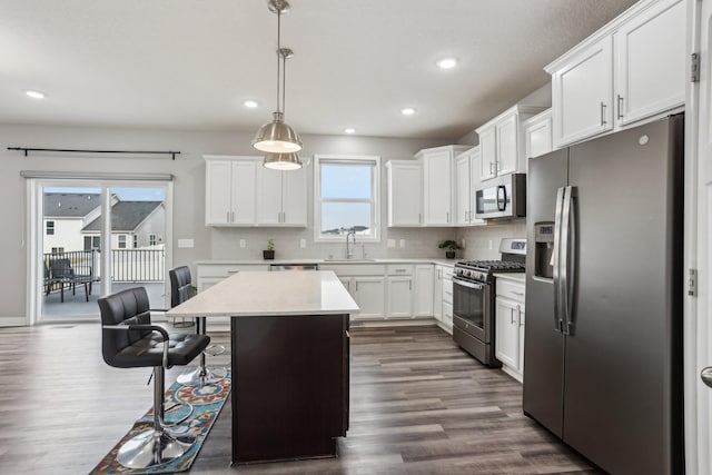 18378 Grasshopper Dr, Lakeville, MN 55044 - kitchen with stainless steel appliances, a sink, dark wood-style flooring, a kitchen breakfast bar, and backsplash