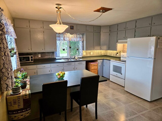 729 10th St E, Wabasha, MN 55981 - kitchen with white appliances, dark countertops, a sink, gray cabinetry, and backsplash