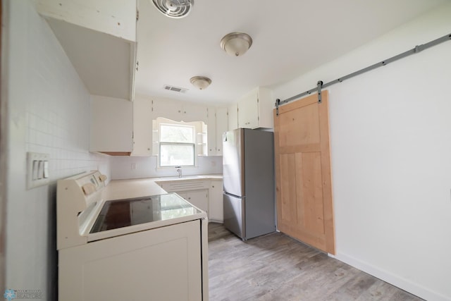 kitchen featuring freestanding refrigerator, white range with electric stovetop, light wood-type flooring, light countertops, and a barn door