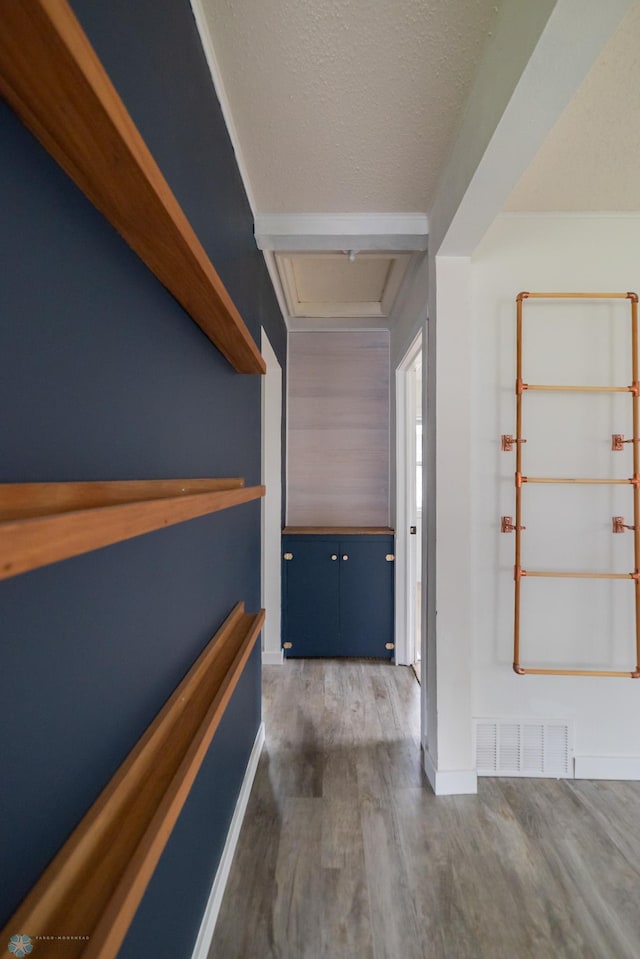 hallway with wood finished floors, a textured ceiling, and baseboards