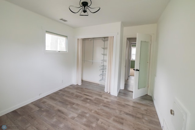 unfurnished bedroom with light wood-style flooring, a closet, and baseboards