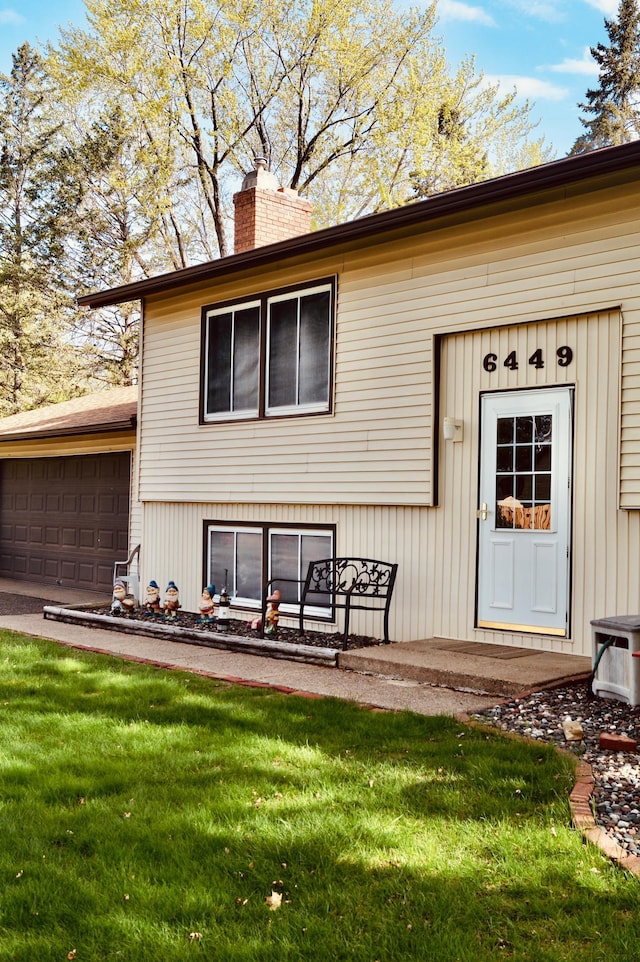 6449 Rice Ct, Lino Lakes, MN 55014 - back of property with a chimney, a garage, and a lawn