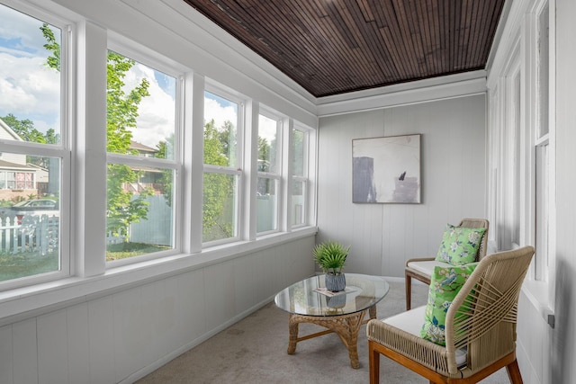sunroom featuring healthy amount of natural light, wood ceiling, carpet, and wood walls