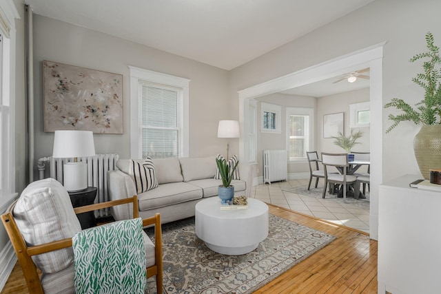 living room with radiator, wood-type flooring, a ceiling fan, and baseboards